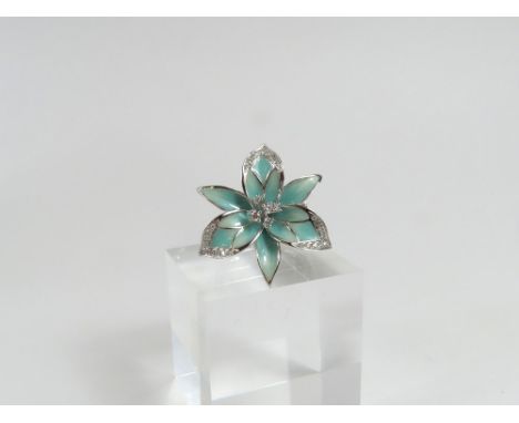 An unusual white gold, pastel green enamel and diamonds, the head of the ring in the form of a flower decorated with enamel a