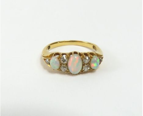 A late Victorian or early 20th century white opal and diamond ring, the central oval cabochon cut opals with pairs of old cut