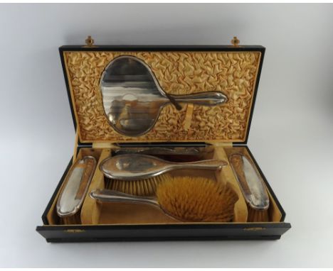 A silver dressing table set in case. Comprises two handled hair brushes, two slim brushes, a comb and a handled mirror. Each 
