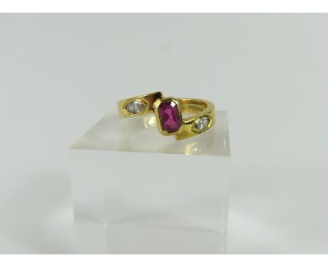An 18ct gold contemporary design ring, the step cut ruby in a rub over setting at a slight angle, approximately 0.94cts, the 