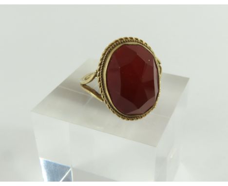 A 9ct gold orange hardstone ring, probably a carnelian, the high stone facetted throughout the top, in a twisted rope setting