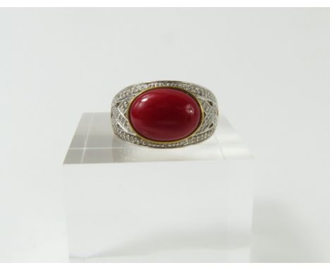 A 9ct gold red coral (possibly dyed) and diamond dress ring, the oval cabochon cut coral stone, approximately 12mm x 8.9mm, s
