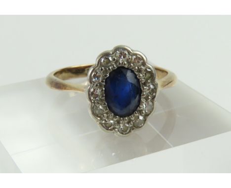 An early 20th century sapphire and diamond cluster ring, the oval cut sapphire surrounded by a row of diamonds, in a daisy st