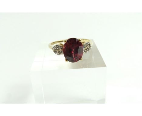 A 9ct gold red zircon and champagne diamond dress ring, the oval cut zircon in a four claw setting, 3.71cts, with six small c