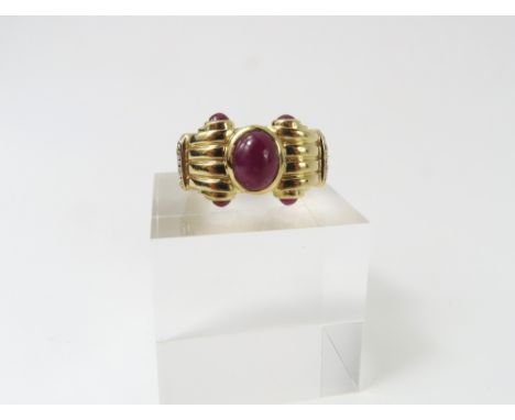 An unusual ruby and diamond dress ring, the central oval cabochon cut ruby rub over set, with heavy decorative shoulders with
