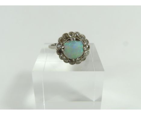 An early to mid-20th century white opal and diamond cluster ring, the cabochon cut oval opal in double claw setting surrounde