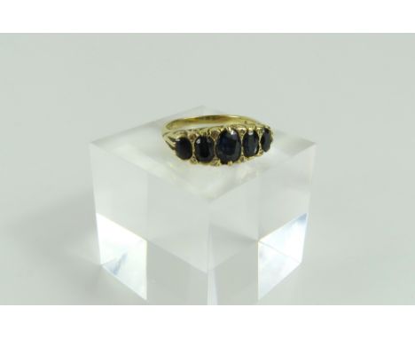 A 19th or early 20th century five stone sapphire ring, the graduated oval cut stones with diamond points, in a heavy carved s