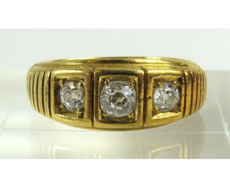 A later 19th or early 20th century three stone diamond ring, the old cut stones in inset four claw settings, with ribbed deco