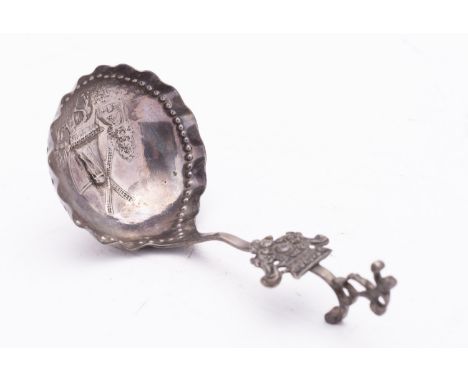 A Dutch silver spoon, stamped mark, the circular bowl with embossed view of a windmill, on a scroll handle with figural termi