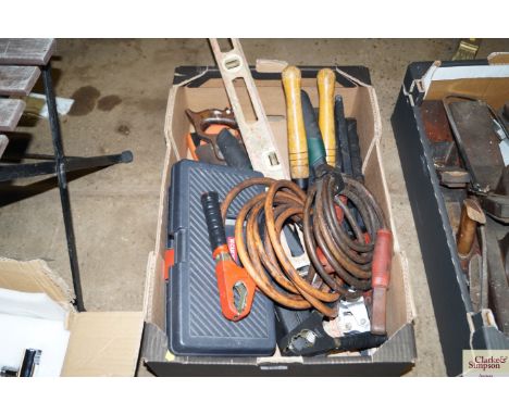 A box of tools including jump leads, level, saws, etc.