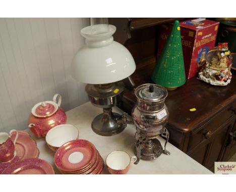 An oil lamp with opaque glass shade and a metal urn on heater stand