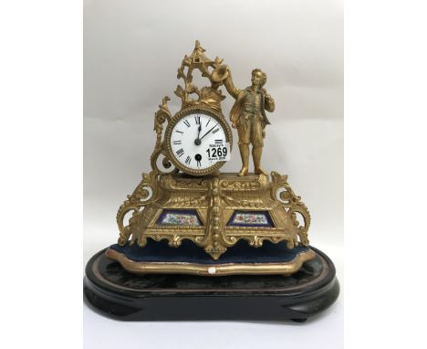 A gilt French mantle clock, the enamel dial with Roman numerals, flanked by a male figure. Inset with porcelain panels under 
