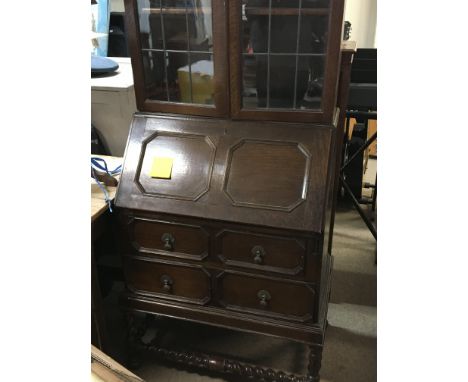 An oak bureau bookcase with lead light glazed doors above a fall front with two drawers on barley twist supports. 65cm wide 2