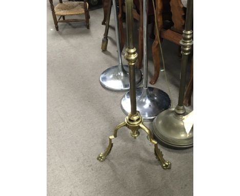 A brass telescopic standard lamp with shaped supports and claw feet.