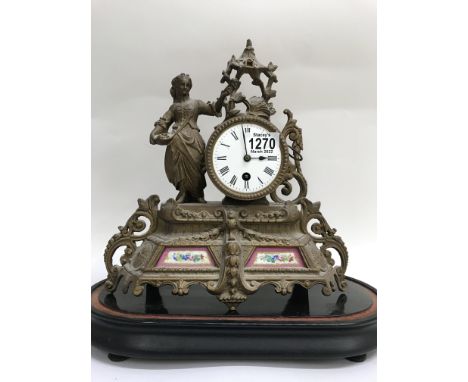 A gilt mantle clock, enamel dial with Roman numerals, flanked by a maiden. Inset with porcelain panels, on ebonized base.