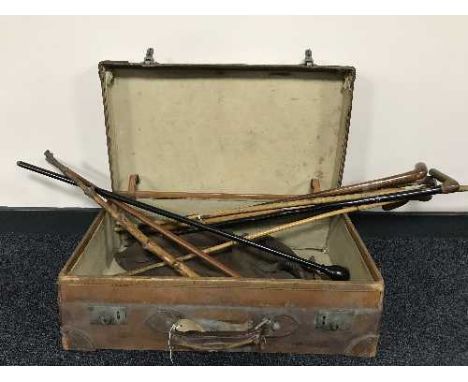 A vintage leather suitcase containing a quantity of walking sticks, together with a box of cuckoo clocks, mantel clock etc
