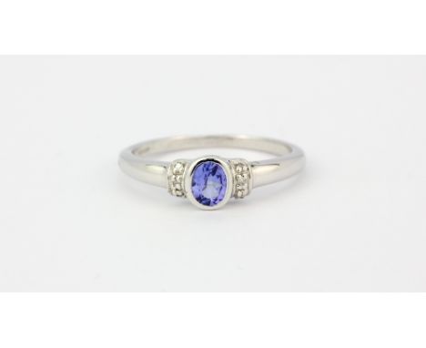 A 9ct white gold ring set with an oval cut tanzanite and diamond set shoulders, (P).