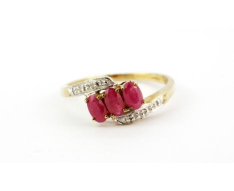 A 9ct yellow gold (stamped 375) crossover ring set with oval cut rubies and diamonds, (P.5).