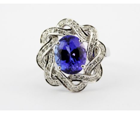 A 14ct white gold (stamped 585) ring set with an oval cut tanzanite surrounded by brilliant cut diamonds, (O)