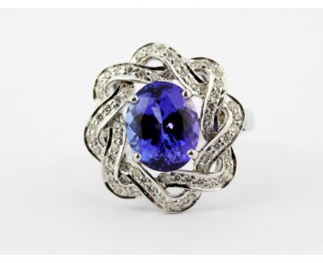 A 14ct white gold (stamped 585) ring set with an oval cut tanzanite surrounded by brilliant cut diamonds, (O)