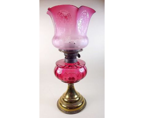 A Victorian oil lamp with cranberry glass etched shade and reservoir