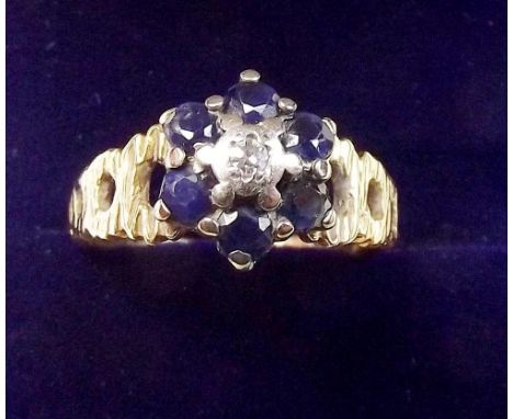 An 18 carat gold sapphire and diamond cluster ring on pierced textured shoulders, size M 1/2