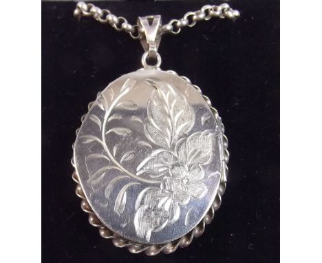 A silver oval engraved locket and chain - 26g in total