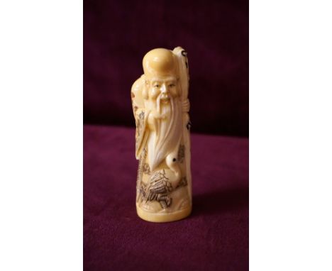 CARVED CHINESE IVORY NETSUKE
depicting an Immortal (Longevity) holding a staff with gourd and a crane at his feet, his robes 