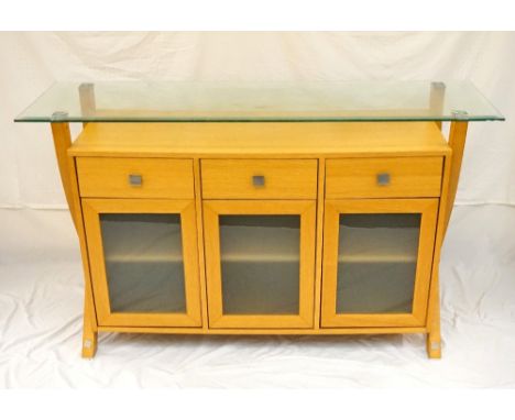 LIGHT OAK SIDEBOARD
with a bevelled edge glass shelf above three frieze drawers with three opaque glass panelled doors below,