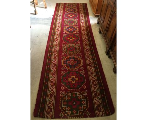 A red patterned wool carpet runner. 95 x 330cm.