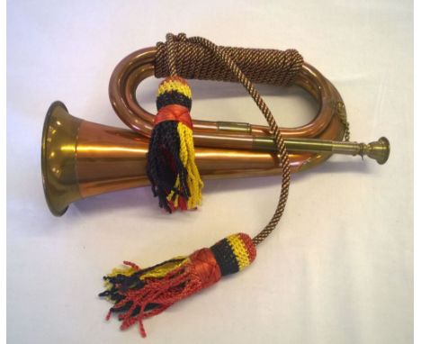 A copper & brass bugle with red, yellow and black cords.