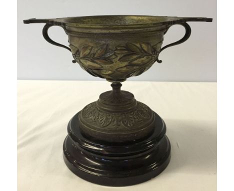 A heavy early 20th century/late 19th century brass cup on ceramic base.