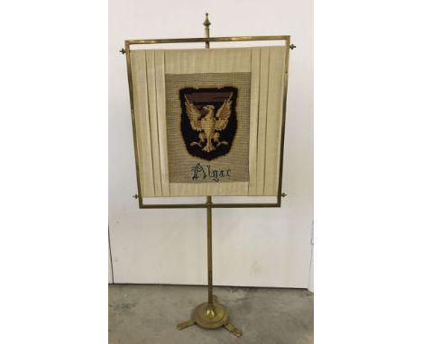 A brass firescreen with tapestry armorial crest.