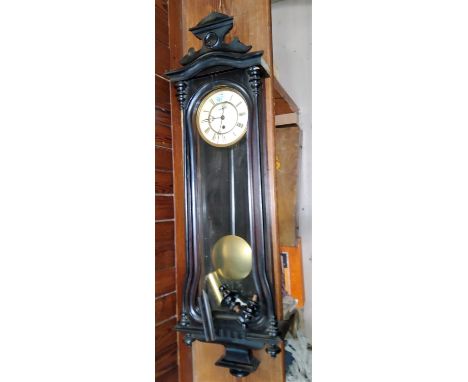 A 19th century Vienna wall clock in ebonised case with raised crest, turned finials and side columns, white enamel dial and s