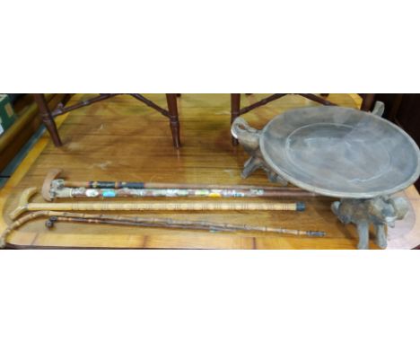 A carved wooden African style bowl with three elephants for feet, a small selection of vintage walking sticks