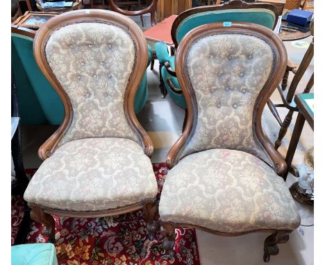 A pair of Victorian mahogany spoon back ladies and gent's armchairs on knurled feet and castors with button backs upholstered