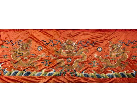 A LARGE CHINESE RED-GROUND EMBROIDERED SILK 'DRAGON' PANEL QING DYNASTYWorked in couched gold threads with three ferocious fi