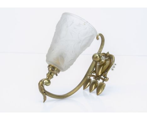 A brass Art Nouveau wall light applique, the brass bracket decorated with three stylised floral heads within a sinuous design