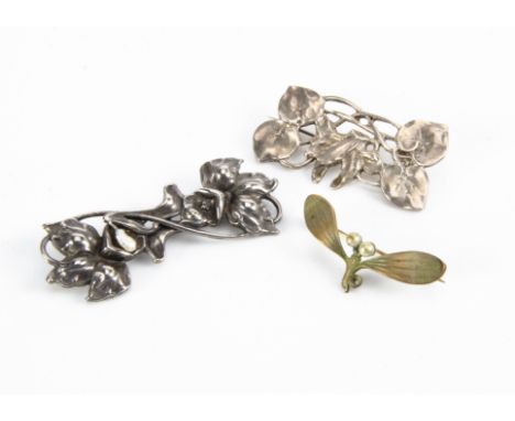 Two white metal floral brooches, one with daffodil design, the other with stylised flower head and sinuous ivy leaf and stems