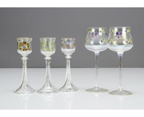 A pair of German Art Nouveau liquor glasses, in the Meyr's Neff style with green and amber floral decoration on a faceted cir