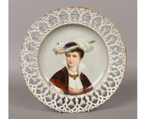 An early 20th century Continental porcelain dish with pierced border. Painted to the centre with the portrait of a lady weari