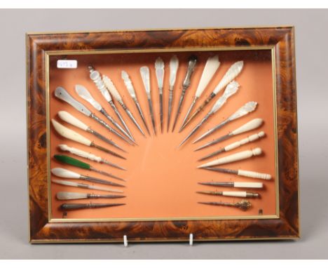 A framed display of mother of pearl and bone handled stiletto shawl sewing tools.