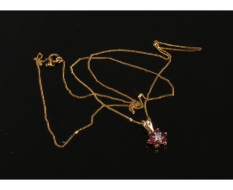 A 9ct gold ruby and diamond cluster pendant on 9ct gold trace chain.