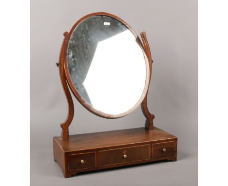 A 19th century oval shaped dressing table mirror crossbanded in satinwood incorporating three drawers, raised on bracket feet