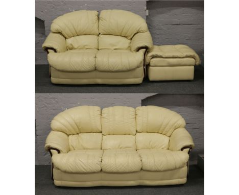 A cream leather three piece suite consisting of three seat sofa with mahogany effect trim, matching two seat sofa and foot st