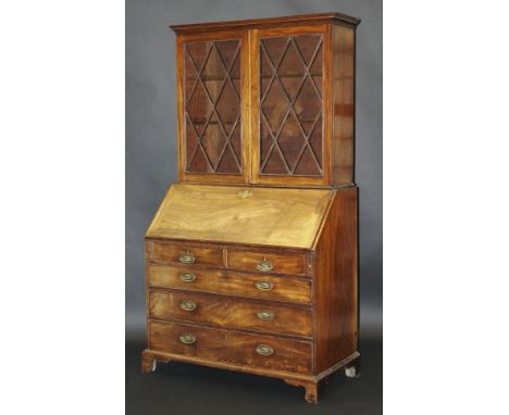 A George III mahogany bureau bookcase, the glazed two door upper section over a sloping fall with fitted stepped interior, ov