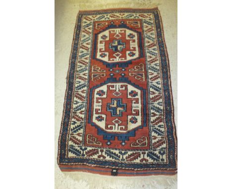 A Turkish rug, the two central medallions in terracotta, cream and blue on a terracotta ground within cream, blue and terraco
