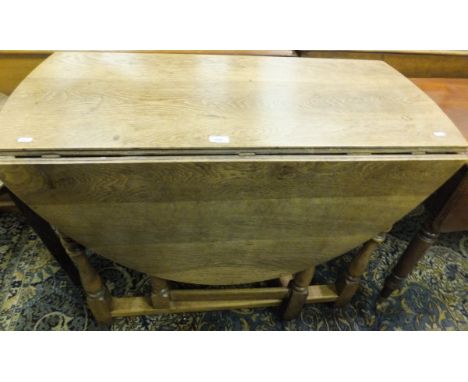An oak oval drop leaf gate leg dining table on baluster form supports