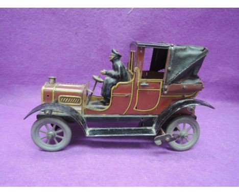 A 1920's tin plate and clockwork Fischer/Bing style vintage car in brown and yellow having driver with leather covered passen