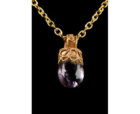 Ca. 323-31 BC  A gold pendant with a circular suspension loop, cylindrical body and amethyst setting. The exteriors of the bo